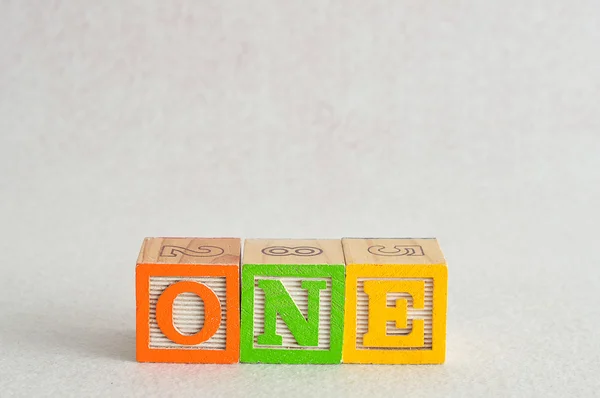 Das Wort one (1) buchstabiert mit bunten Buchstabenblöcken — Stockfoto