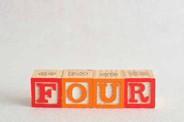 Das Wort vier (4) buchstabiert mit bunten Buchstabenblöcken — Stockfoto