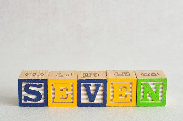 The word seven (7) spelled with colorful alphabet blocks — Stock Photo, Image