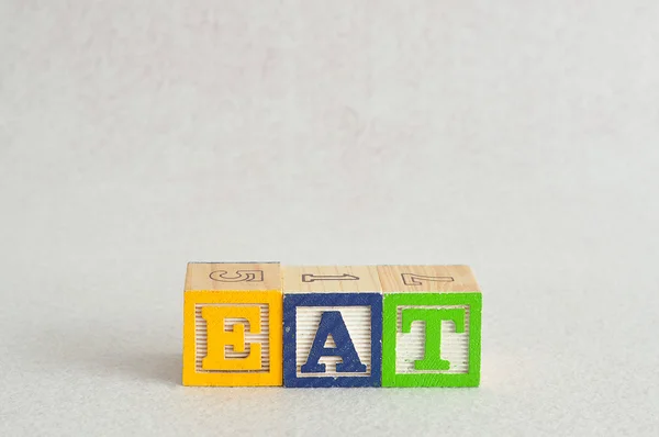 La palabra comer deletreado con bloques de alfabeto — Foto de Stock
