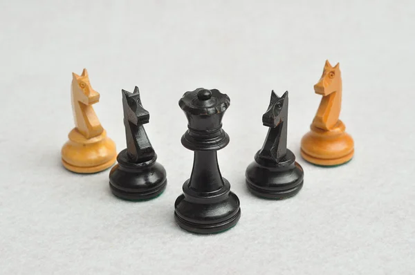 Черная королева с четырьмя фигурами рыцаря на белом фоне — стоковое фото