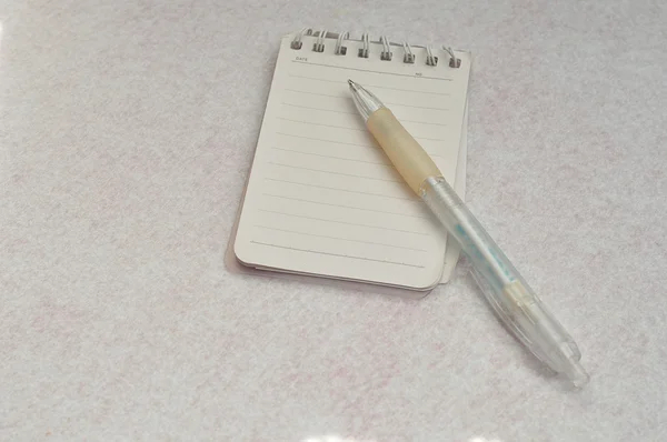 Um pequeno bloco de notas com uma caneta branca — Fotografia de Stock