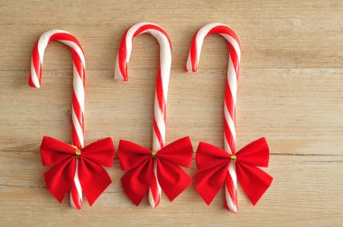 Ahşap arka plan üzerinde izole kırmızı yay ile üç baston şekerler