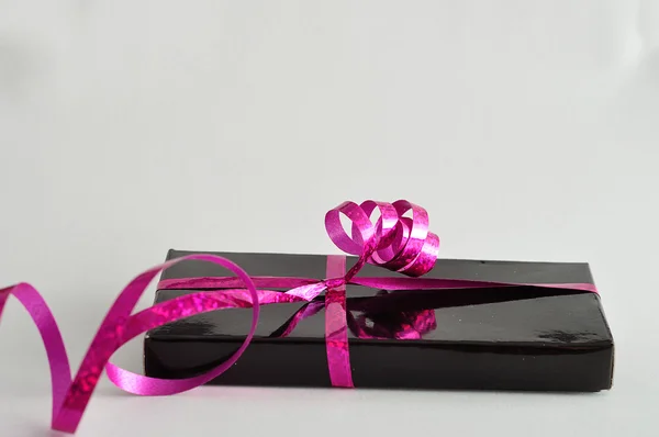 En svart presentbox dekorerad med en rosa bandet — Stockfoto
