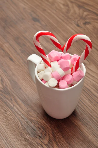 Una taza llena de malvaviscos pequeños con dos bastones de caramelo — Foto de Stock