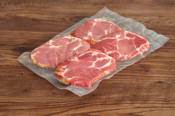 Próżniowo pakowane mięso wyświetlane na tle drewnianych Obraz Stockowy