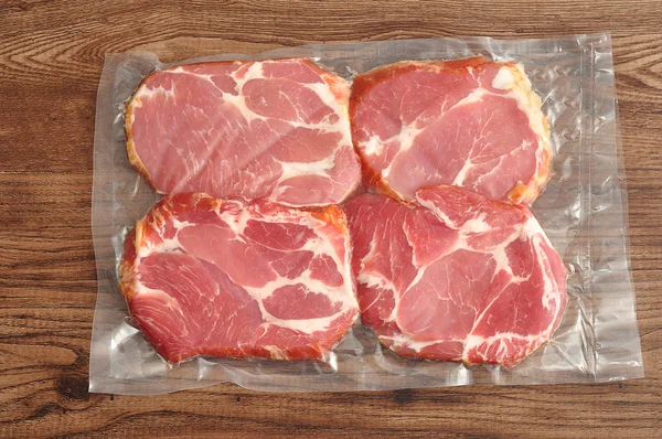 Próżniowo pakowane mięso wyświetlane na tle drewnianych Zdjęcie Stockowe