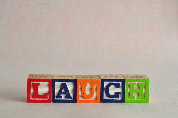 Το γέλιο λέξη γράφεται με πολύχρωμο μπλοκ — Φωτογραφία Αρχείου