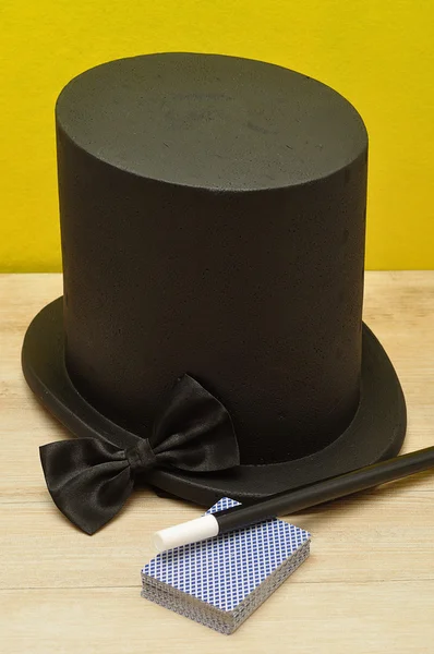 Um chapéu mágico exibido com uma varinha, gravata borboleta e cartas — Fotografia de Stock