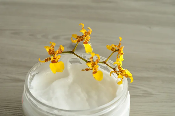 Body lotion in a container with yellow orchids