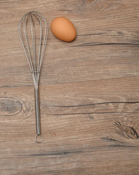 An egg beater, whisk, with one egg
