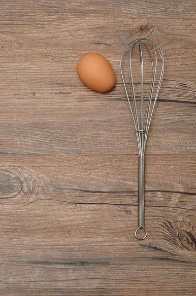 Un batidor de huevos, batidor, con un huevo — Foto de Stock