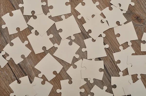 Ahşap arka plan üzerinde beyaz puzzle parçaları