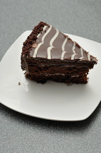 Una deliziosa fetta di torta al cioccolato in un piatto bianco — Foto Stock