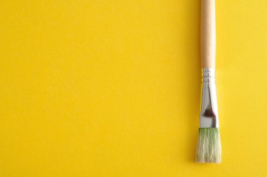 Sarı bir arka plan üzerinde izole bir boya fırçası