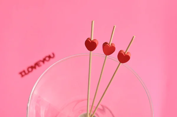 Dia dos Namorados. Três corações vermelhos em paus em um copo de martini — Fotografia de Stock