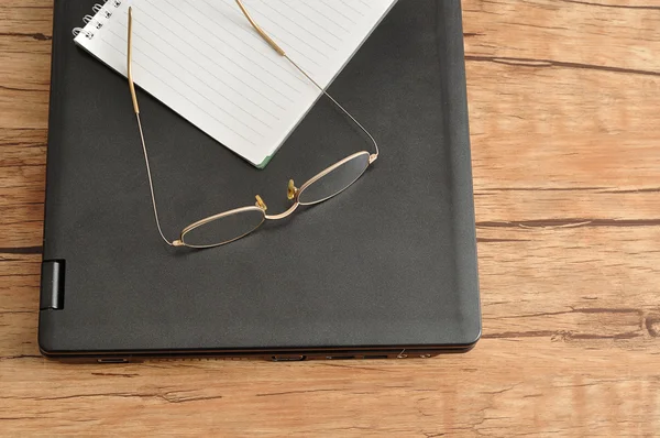 Laptop with a notebook and reading glasses — Stock Photo, Image