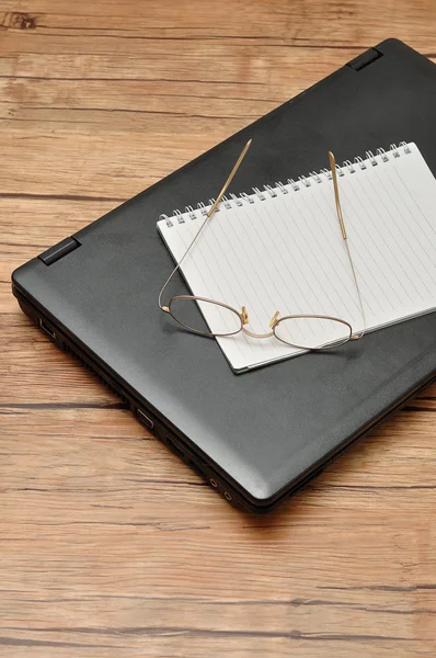 Laptop with a notebook and reading glasses — Stock Photo, Image
