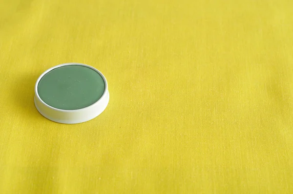 Een groene zalf in een witte tin geïsoleerd op een gele achtergrond — Stockfoto