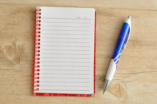 Caderno aberto com páginas brancas alinhadas e uma caneta azul — Fotografia de Stock