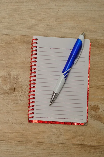 Caderno aberto com páginas brancas alinhadas e uma caneta azul — Fotografia de Stock