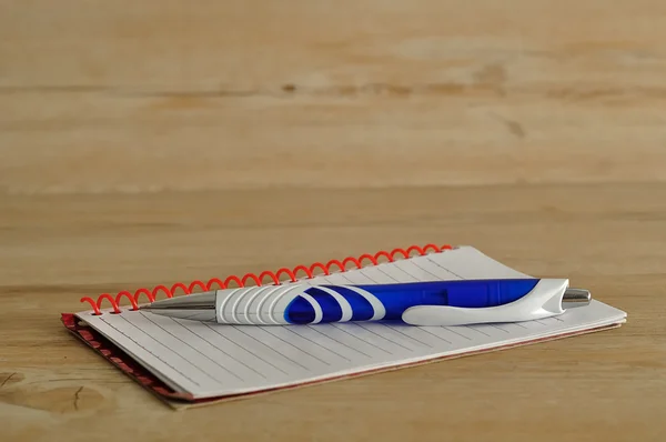 Açık defter ile beyaz çizgili sayfalar ve mavi bir kalem — Stok fotoğraf