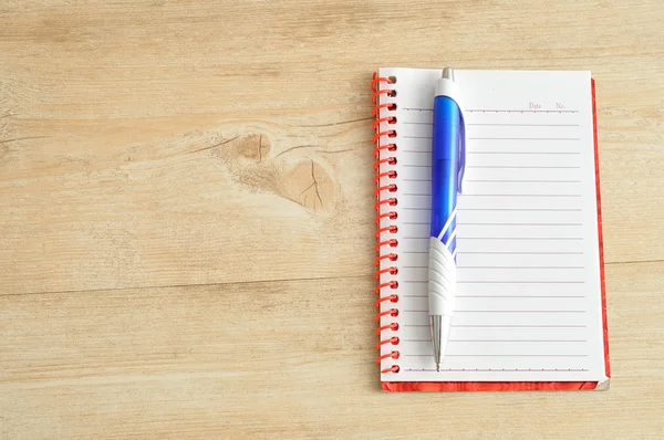 Caderno aberto com páginas brancas alinhadas e uma caneta azul — Fotografia de Stock