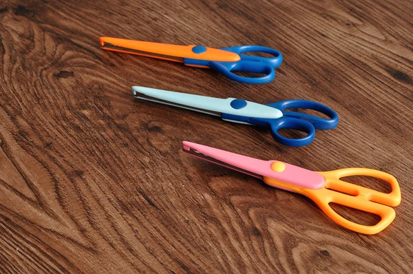 Colorful scissors isolated on a wooden background — Stock Photo, Image