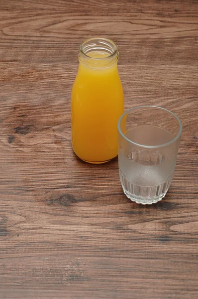 Sumo de laranja numa garrafa com um copo vazio — Fotografia de Stock
