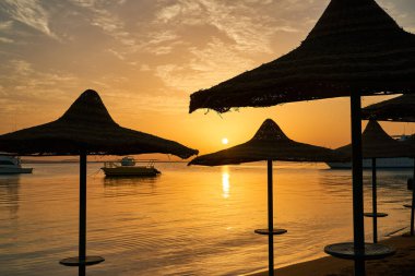 Güzel bir denizde kumlu bir sahilde gün batımı