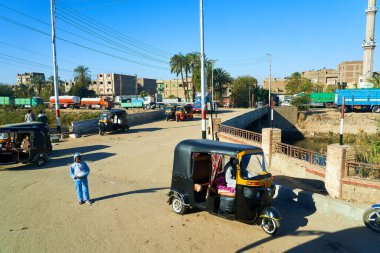 Qena, Mısır - 30 Ocak 2021 - Fakir insanlar ve üç tekerlekli küçük taksici kenar mahalleli şehir sokakları