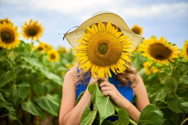 Kız yüzünün önünde bir ayçiçeği tutuyor. Sivilce ve cilt bakımı konsepti