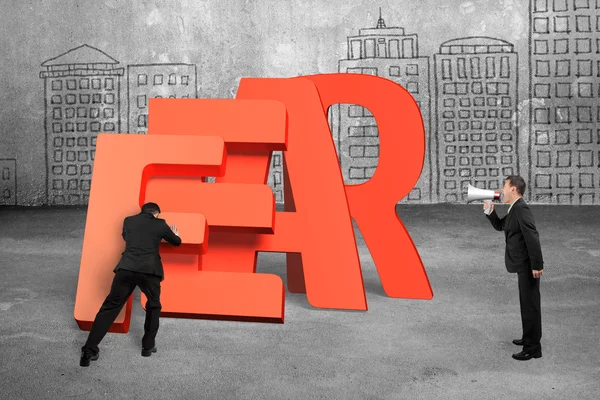 Man pushing fear word domino falling with another holding speake — Stock Photo, Image