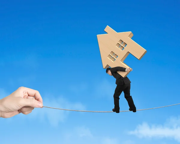 Man carrying wooden house and balancing on tightrope — Stock Photo, Image