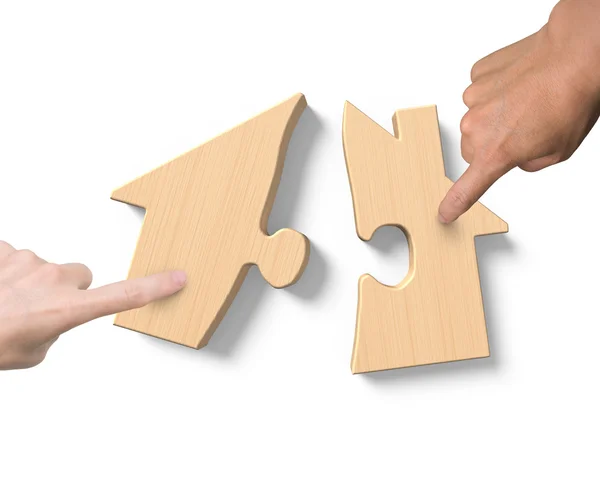 Duas mãos montando quebra-cabeças de forma de casa de madeira — Fotografia de Stock