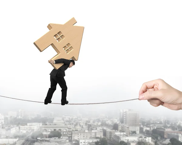 Man carrying wooden house and balancing on tightrope — Stock Photo, Image