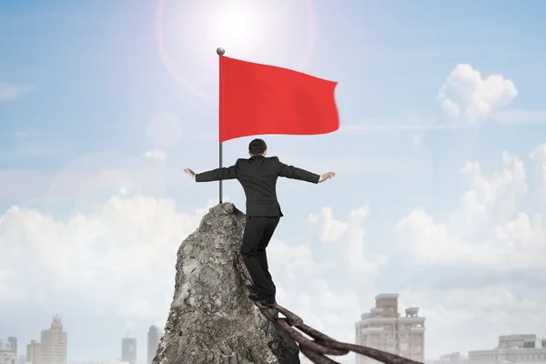 Hombre balanceándose en cadena oxidada para bandera en la cima de la montaña —  Fotos de Stock