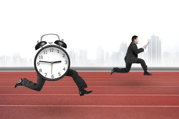 Alarm clock of running legs running after man holding tablet — Stockfoto