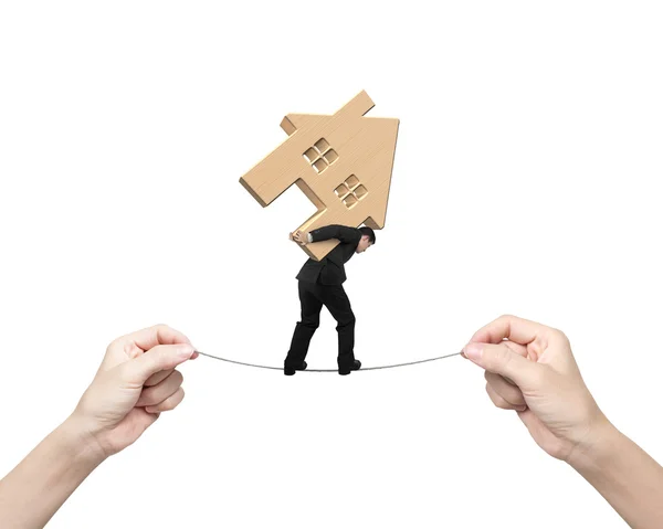 Man carrying wooden house and balancing on tightrope — Stock Photo, Image