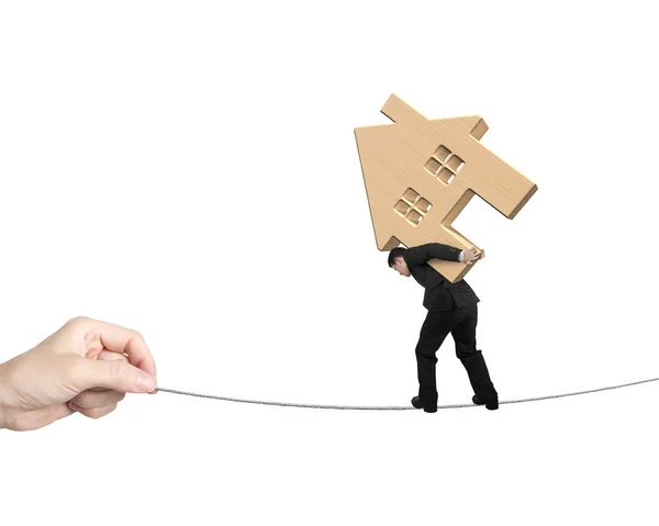 Man carrying wooden house and balancing on tightrope — Stock Photo, Image