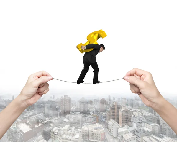 Man carrying dollar sign balancing tightrope with hands holding — Stock Photo, Image