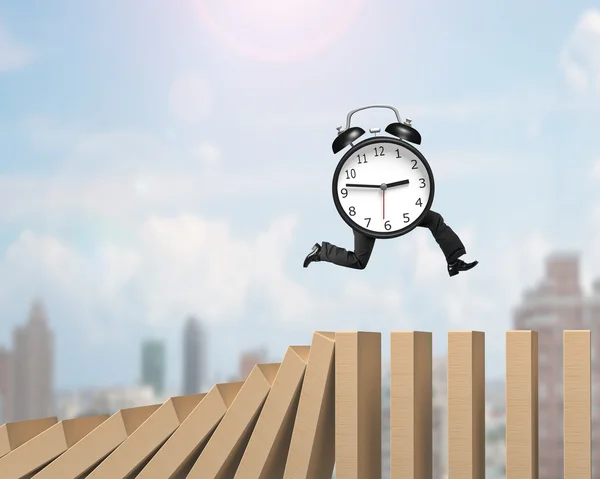 Alarm clock with legs running on falling dominoes — Stock Photo, Image