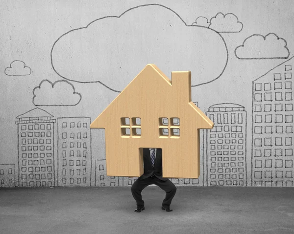 Businessman holding lifting wooden house up — Stock Photo, Image