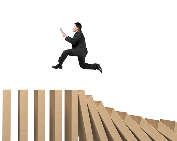 Man using digital tablet running on falling wooden dominos — Stock Photo, Image