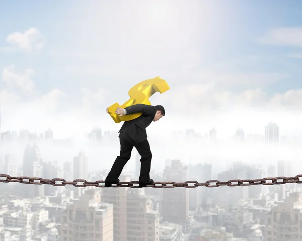 Man carrying golden dollar sign balancing on chain — Stock Photo, Image