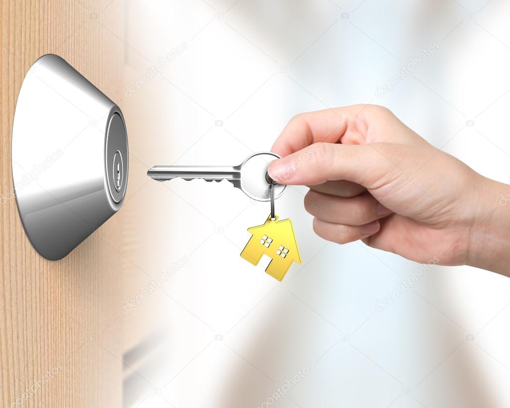 Hand holding key with house shape key-ring to unlock