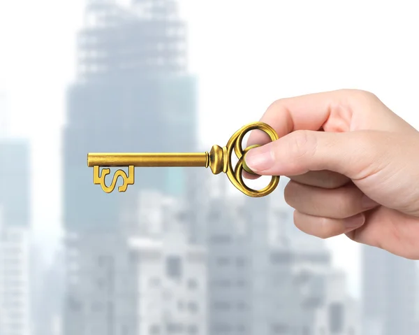 Hand holding golden treasure key in dollar sign shape — Stock Photo, Image