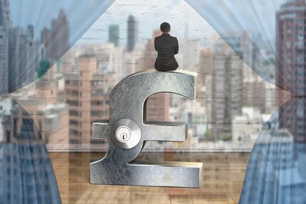 Businessman sitting on silver pound symbol with lock — Stock Photo, Image