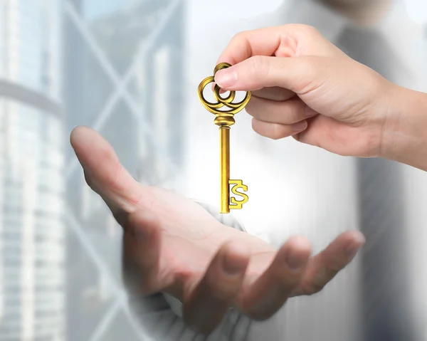 Woman hand giving dollar sign treasure key to man hand — Stock Photo, Image