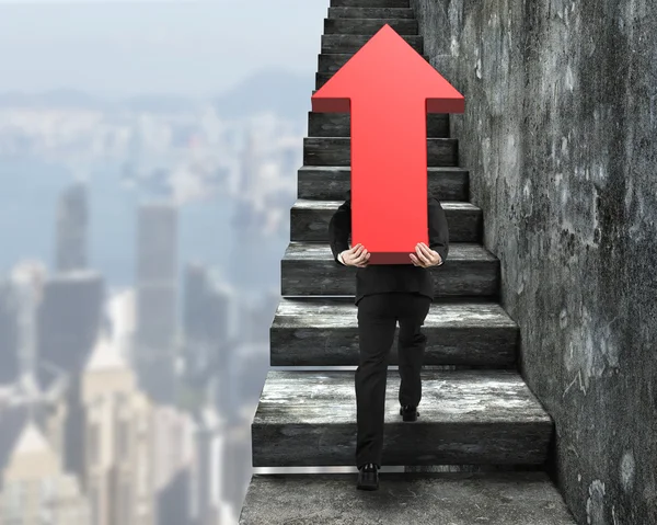 Empresario llevando un cartel de flecha roja subiendo escaleras — Foto de Stock